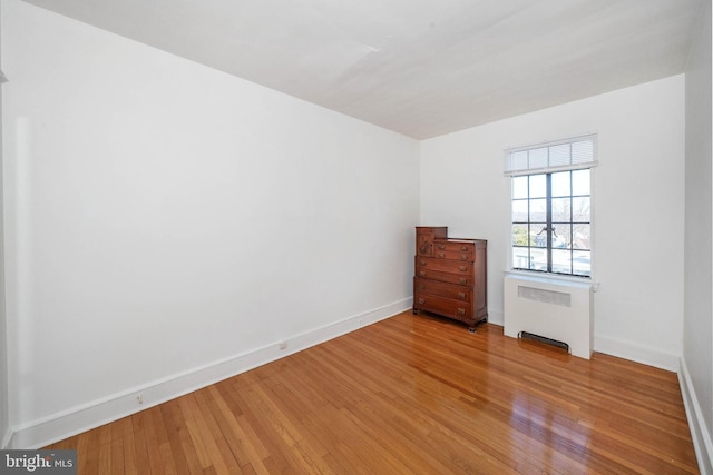 spare room featuring radiator heating unit and light hardwood / wood-style floors