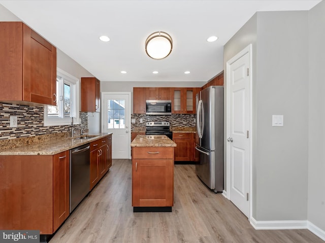 kitchen featuring sink, stainless steel appliances, light stone counters, light hardwood / wood-style floors, and a kitchen island