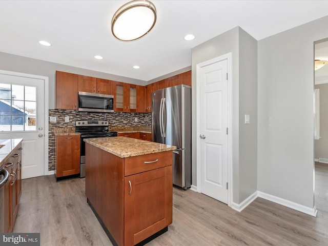 kitchen featuring light stone counters, decorative backsplash, appliances with stainless steel finishes, and a kitchen island