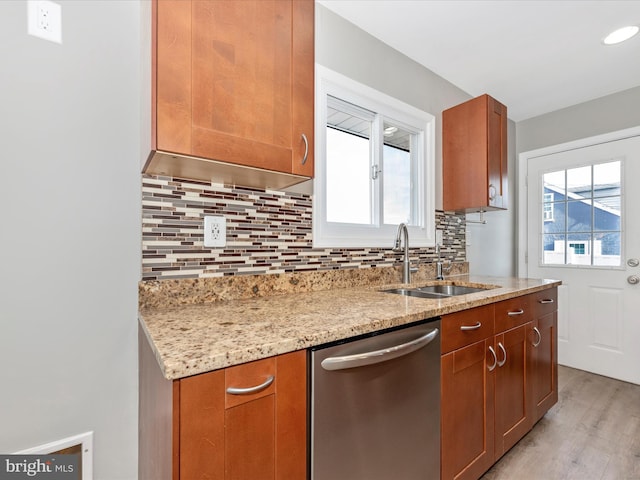 kitchen featuring sink, light hardwood / wood-style flooring, light stone countertops, decorative backsplash, and stainless steel dishwasher