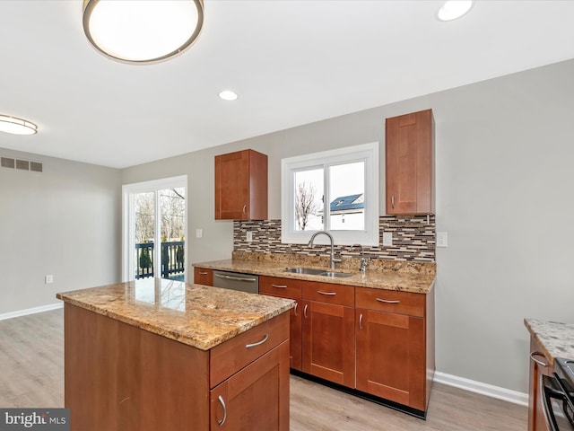 kitchen with a center island, sink, stainless steel dishwasher, and light stone counters