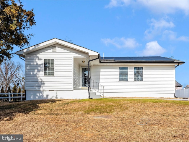 view of front of house featuring solar panels and a front lawn