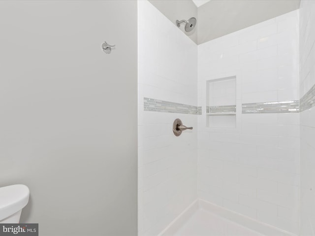 bathroom featuring toilet and a tile shower