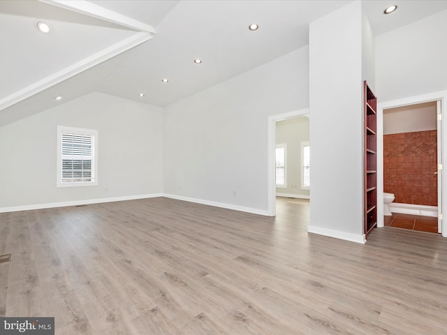 unfurnished living room featuring vaulted ceiling and light hardwood / wood-style flooring