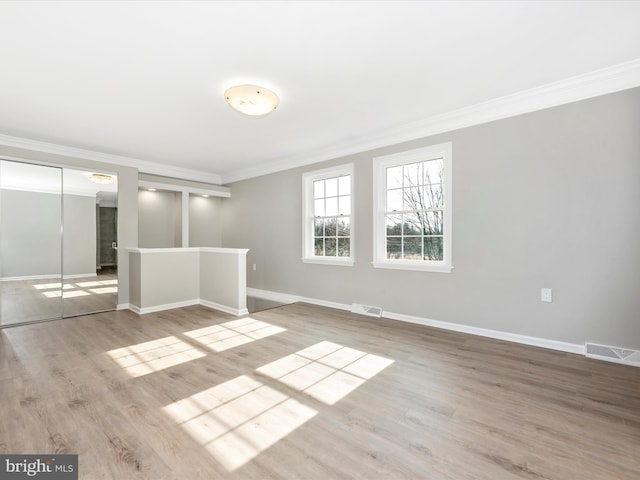 spare room featuring crown molding and light wood-type flooring