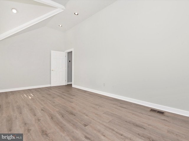 empty room with high vaulted ceiling and light wood-type flooring