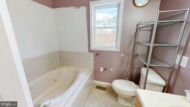 bathroom with visible vents, toilet, vanity, a jetted tub, and baseboards