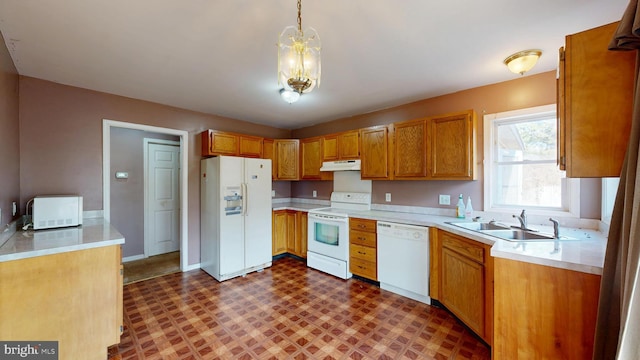 kitchen with dark floors, light countertops, a sink, white appliances, and under cabinet range hood