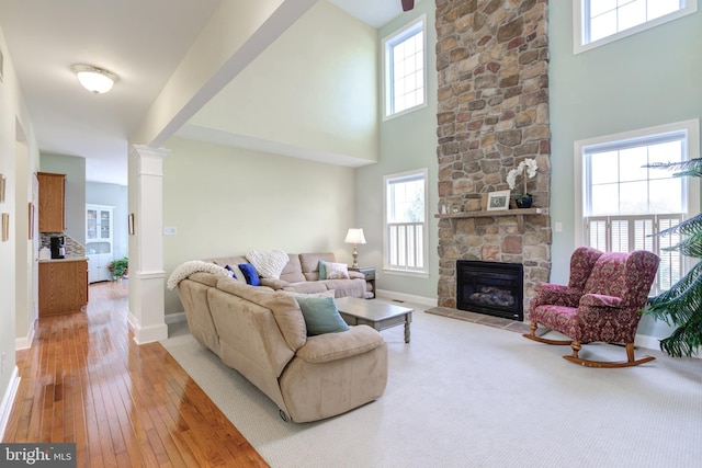 living room with ornate columns, wood-type flooring, plenty of natural light, and a fireplace