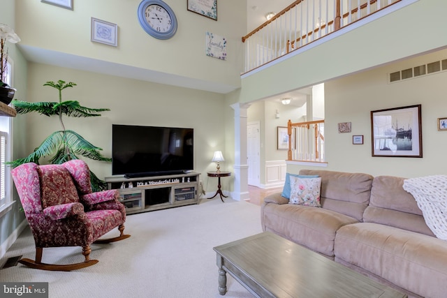 carpeted living room with a towering ceiling and ornate columns