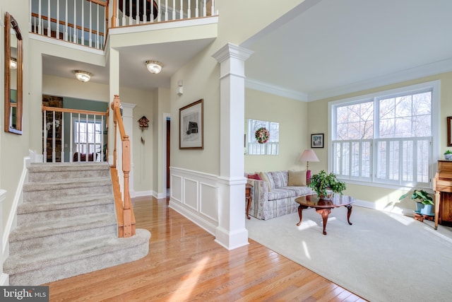 interior space featuring crown molding, light hardwood / wood-style flooring, and ornate columns