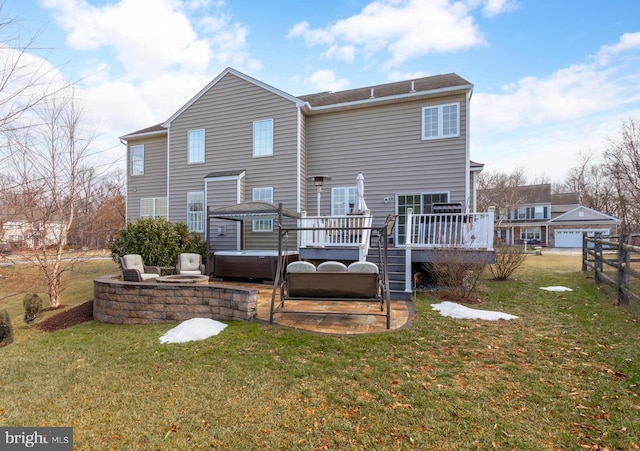 rear view of house with a wooden deck, a garage, a hot tub, and a lawn