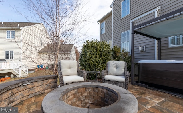 view of patio / terrace with a hot tub and a fire pit