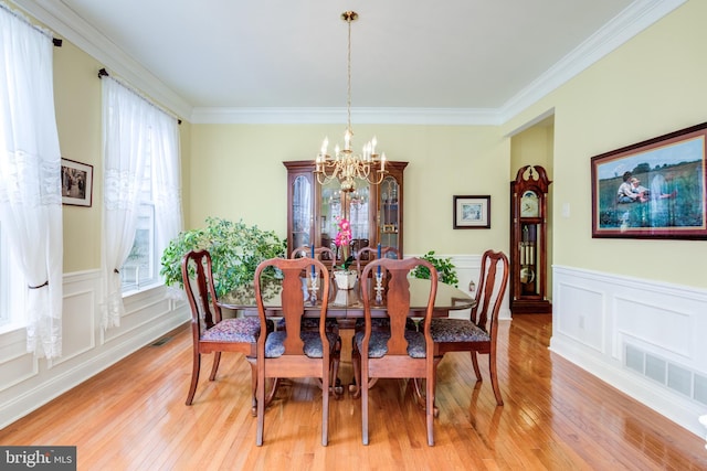 dining area with an inviting chandelier, crown molding, light hardwood / wood-style floors, and a wealth of natural light