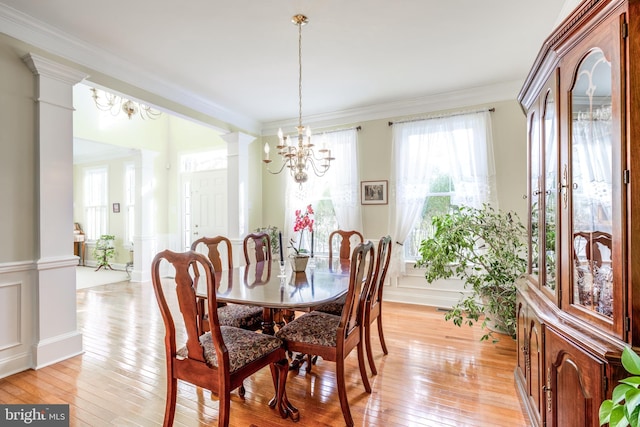 dining room featuring decorative columns, ornamental molding, an inviting chandelier, and light wood-type flooring