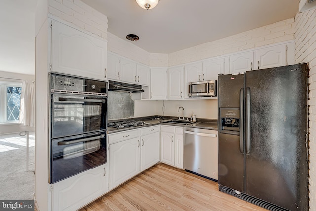 kitchen featuring white cabinetry, sink, light hardwood / wood-style flooring, and black appliances