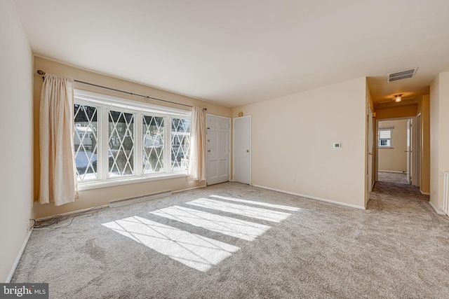 spare room with light carpet and a baseboard heating unit