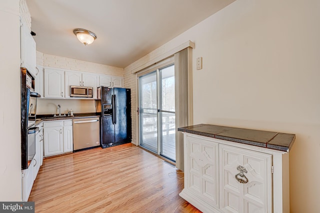 kitchen with appliances with stainless steel finishes, sink, light hardwood / wood-style flooring, and white cabinets