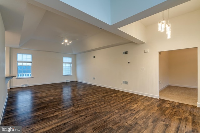 spare room with dark wood-type flooring, a chandelier, and a tray ceiling