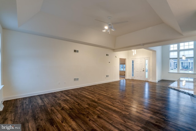 unfurnished living room featuring dark hardwood / wood-style flooring, a raised ceiling, and ceiling fan