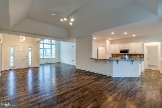 kitchen featuring stone counters, a breakfast bar, dark hardwood / wood-style floors, white cabinetry, and kitchen peninsula