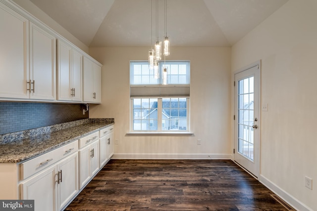 kitchen with dark wood-type flooring, stone counters, white cabinetry, a healthy amount of sunlight, and vaulted ceiling