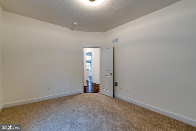 unfurnished room featuring a textured ceiling and carpet