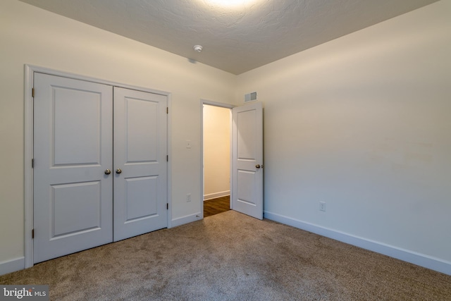 unfurnished bedroom featuring carpet, a textured ceiling, and a closet