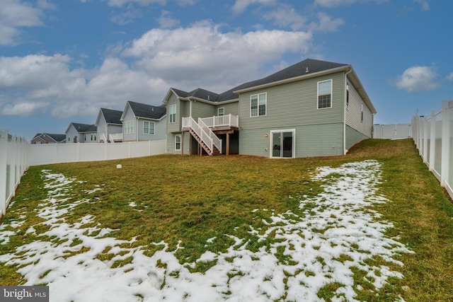 snow covered back of property featuring a wooden deck and a yard