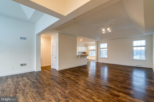 unfurnished living room with a healthy amount of sunlight, dark hardwood / wood-style floors, and ceiling fan