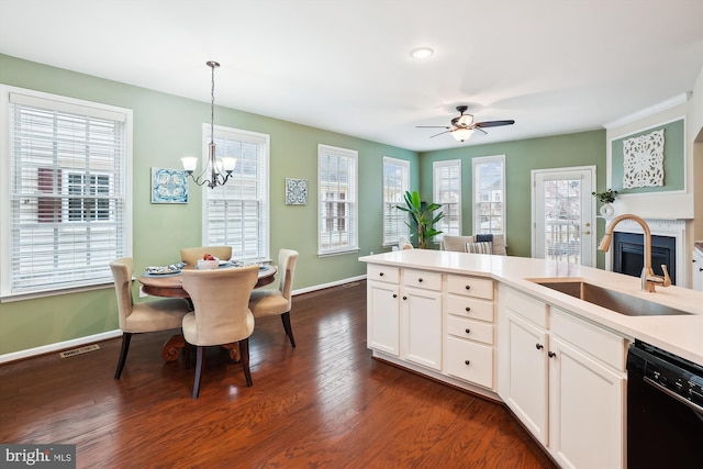 kitchen featuring dark hardwood / wood-style floors, dishwasher, white cabinetry, sink, and hanging light fixtures