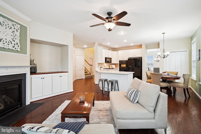 living room with dark wood-type flooring, sink, and ceiling fan with notable chandelier