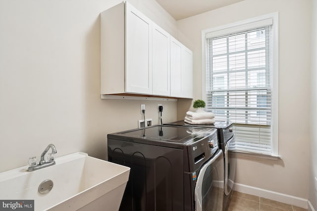 clothes washing area featuring sink, light tile patterned floors, washer and clothes dryer, and cabinets