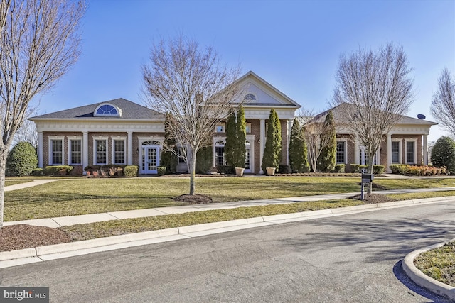 greek revival house with a front lawn and french doors