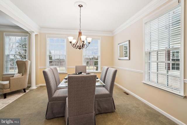 carpeted dining area featuring an inviting chandelier, crown molding, and ornate columns