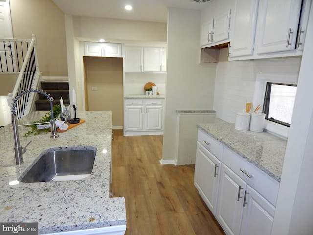 kitchen featuring light stone counters, sink, backsplash, and white cabinets