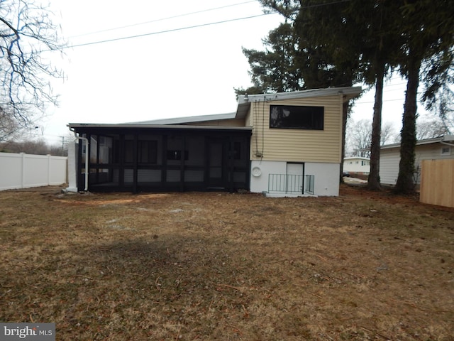 rear view of house featuring a lawn and a sunroom