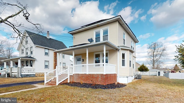 view of front of property featuring cooling unit, covered porch, and a front yard