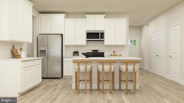 kitchen featuring stainless steel appliances, light hardwood / wood-style floors, an island with sink, and white cabinets