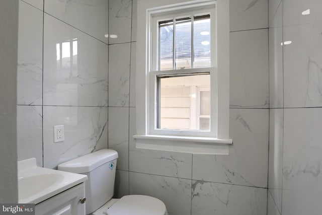 bathroom with vanity, tile walls, and toilet