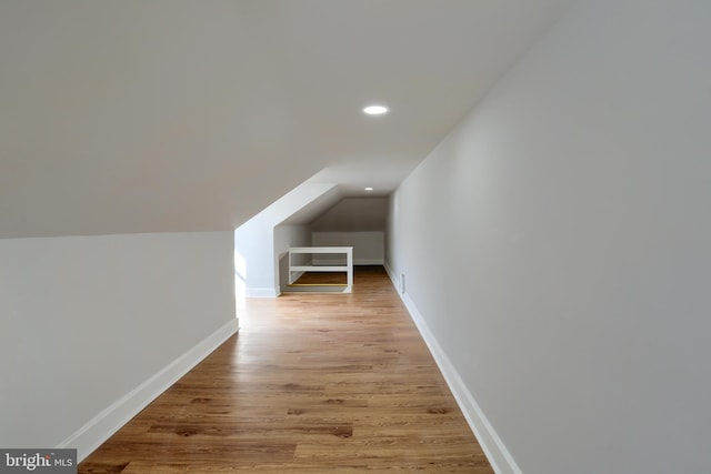 additional living space with vaulted ceiling and light hardwood / wood-style flooring