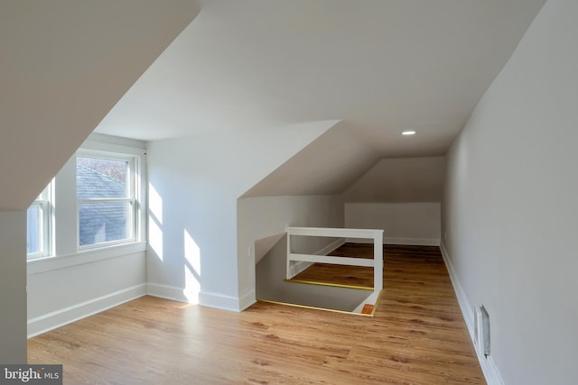 additional living space featuring lofted ceiling and light hardwood / wood-style flooring