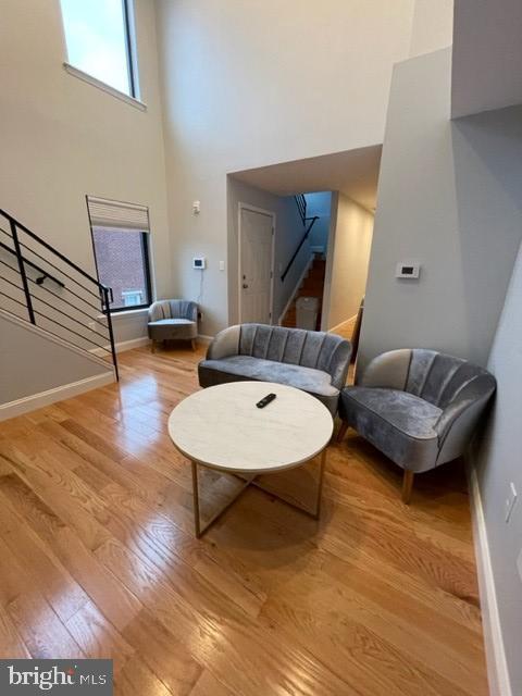 living room featuring hardwood / wood-style floors, plenty of natural light, and a towering ceiling