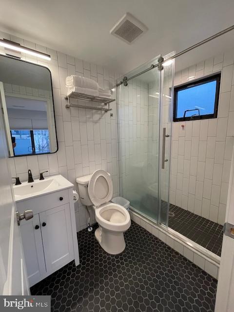 bathroom featuring tile walls, an enclosed shower, vanity, and toilet