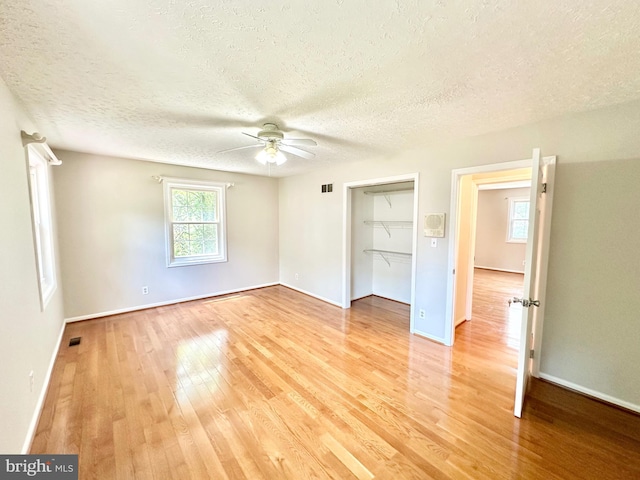 unfurnished bedroom with ceiling fan, hardwood / wood-style floors, a closet, and a textured ceiling