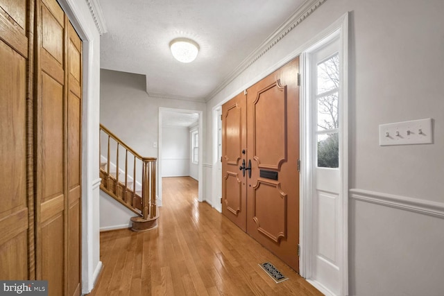 foyer with ornamental molding and light hardwood / wood-style floors