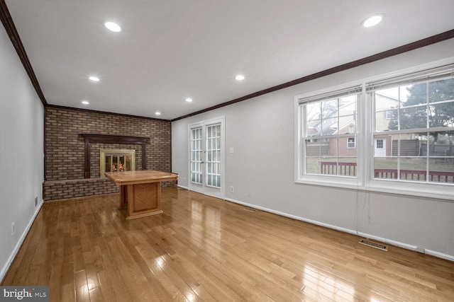 unfurnished living room with crown molding, a fireplace, and light wood-type flooring