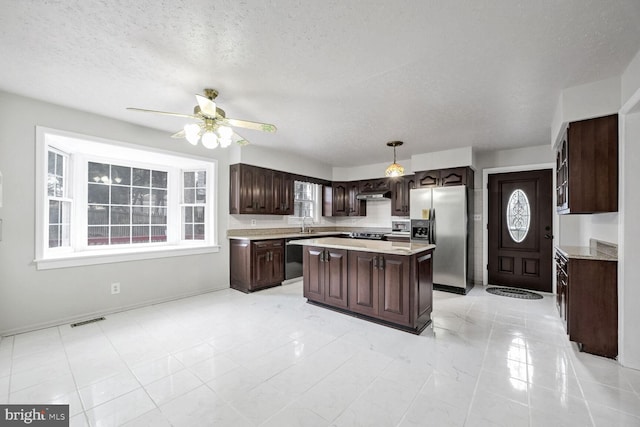 kitchen featuring a kitchen island, decorative light fixtures, ceiling fan, dark brown cabinetry, and stainless steel appliances