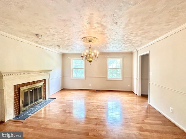 unfurnished living room with hardwood / wood-style flooring, crown molding, a brick fireplace, and an inviting chandelier