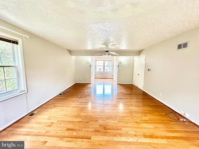 unfurnished room with ceiling fan, light hardwood / wood-style flooring, and a textured ceiling